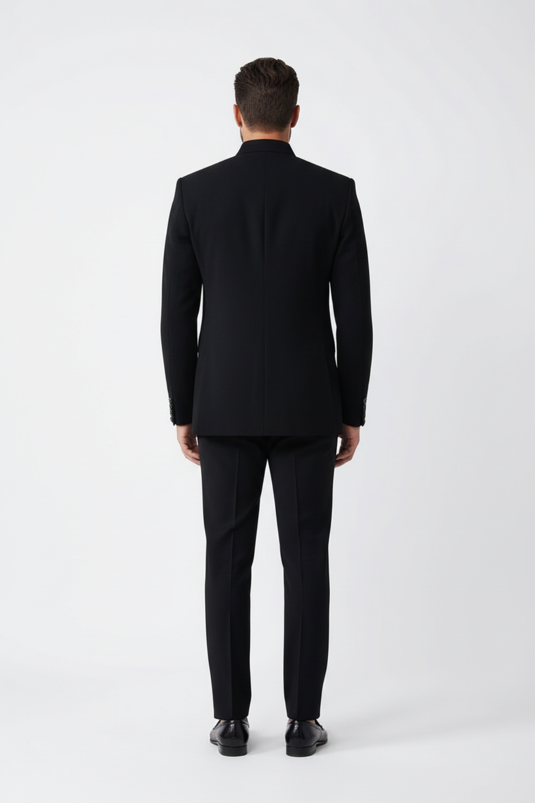 Man wearing a black suit standing against a white background