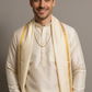 Man wearing a cream kurta with a yellow shawl against a gray background