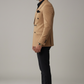 Man wearing a beige blazer and black pants on a gray background