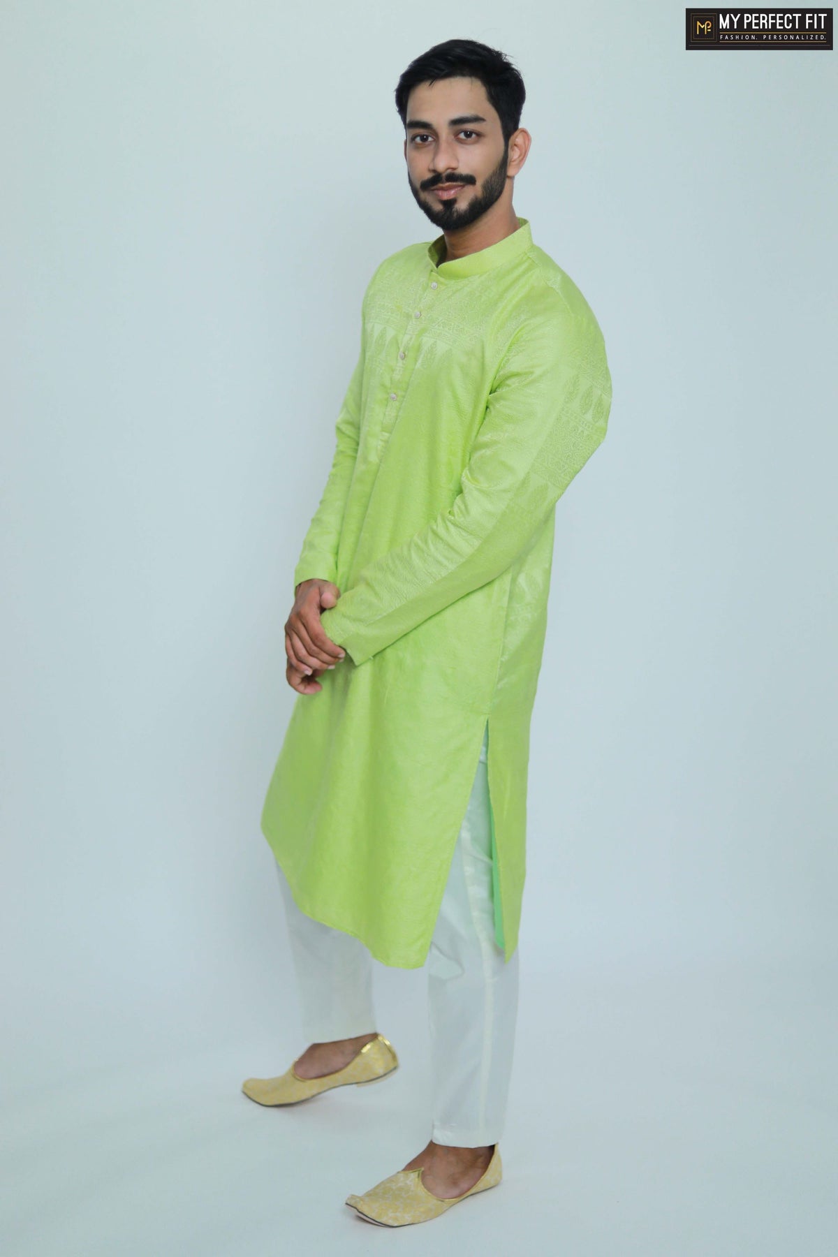 A person standing against a white background, wearing a green jacquard kurta with full-length sleeves, paired with white trousers.