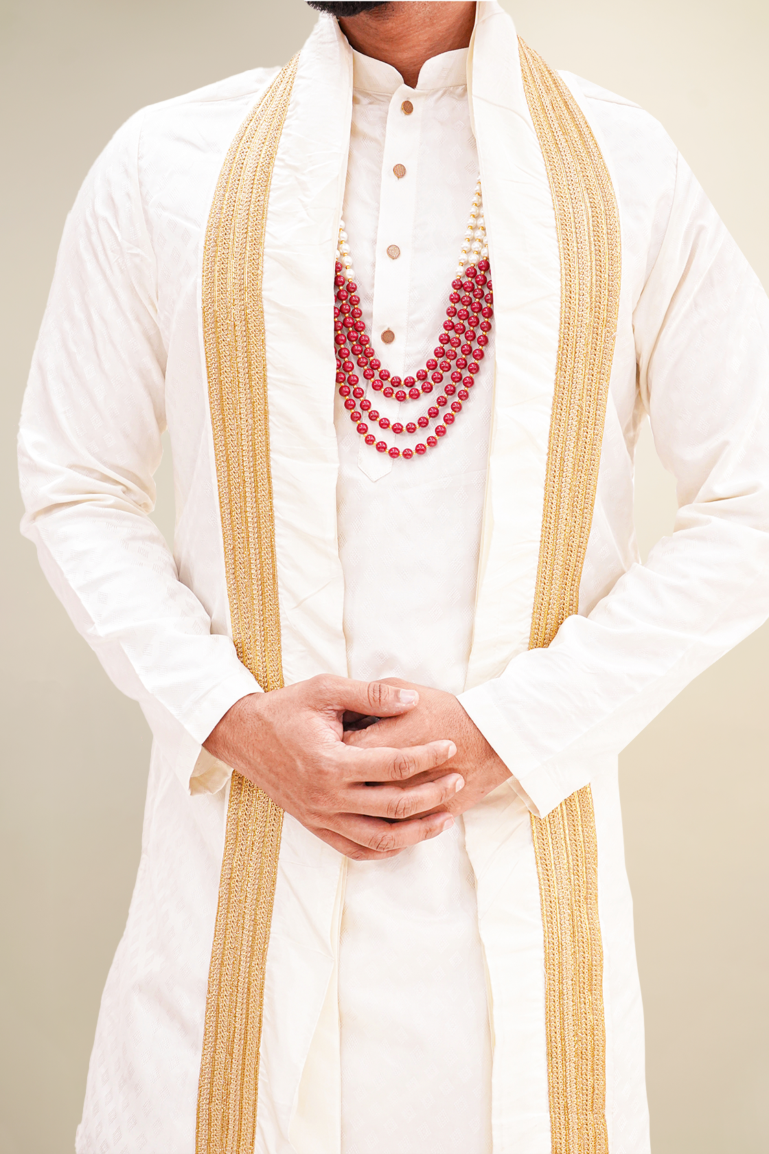 A man wearing a white plain pure pattu kurta set with golden borders and a red necklace.