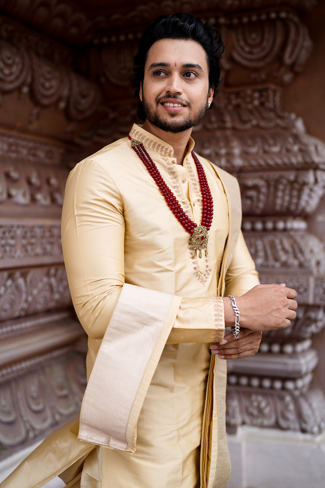 Man in traditional attire with intricate background