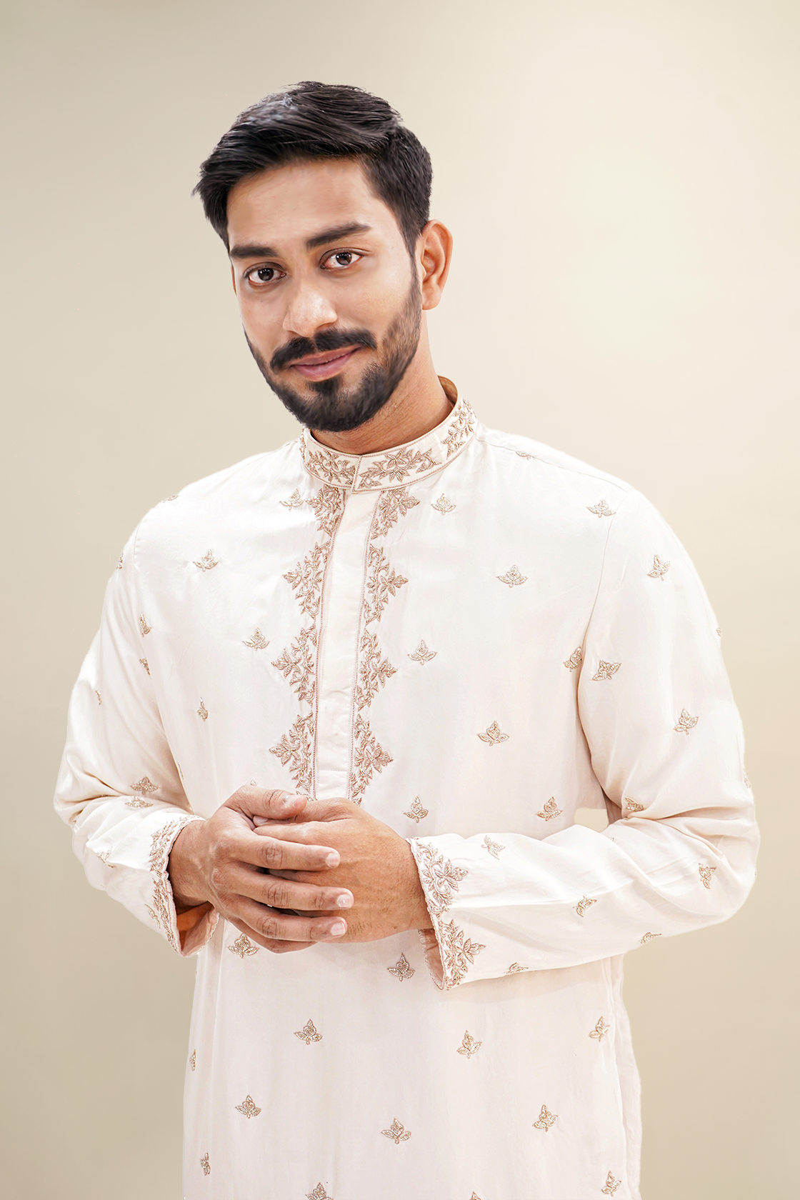 A man wearing a rose pink habutai kurta with zardozi butta work, standing with a smile.