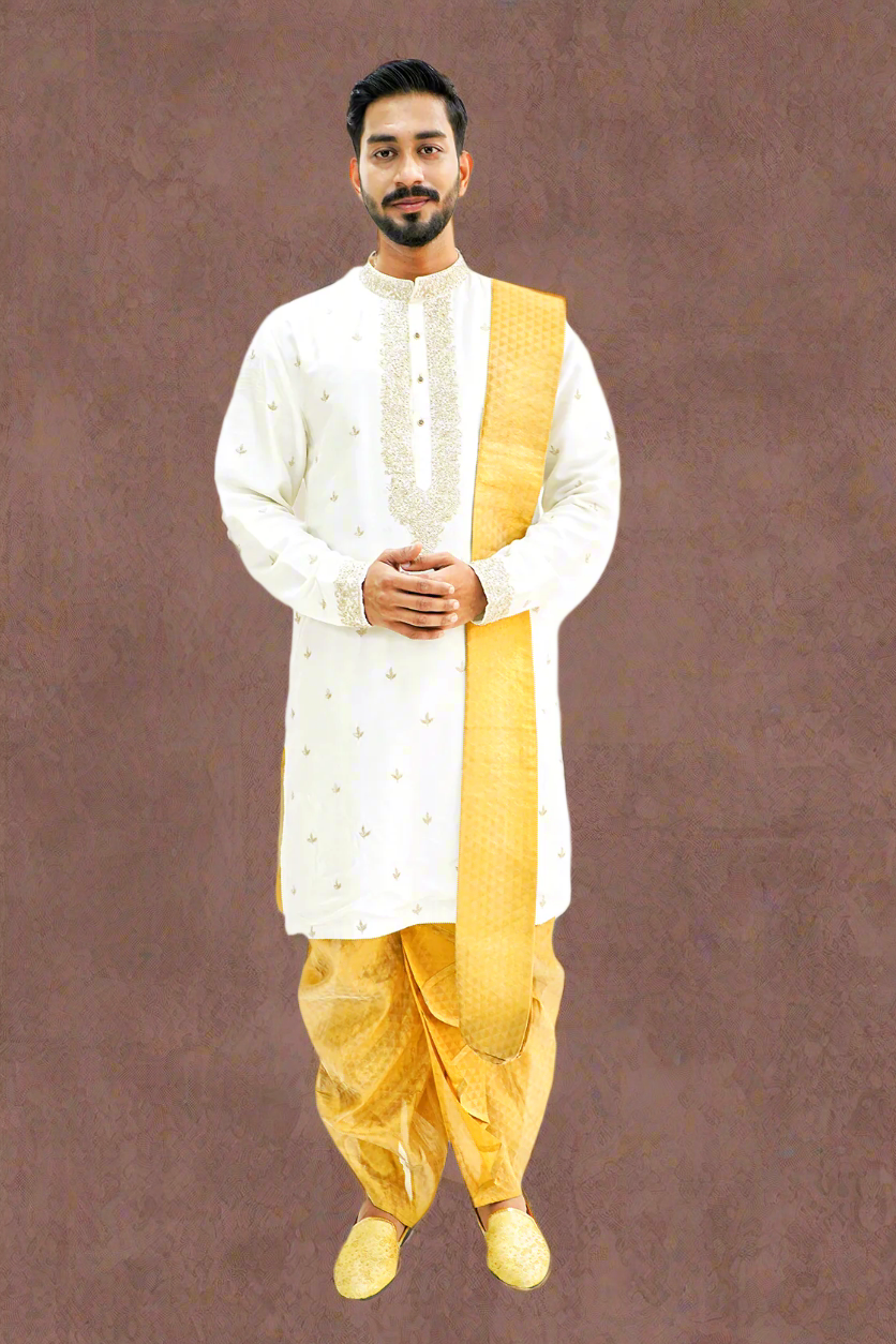 A man wearing a light cream silk kurta with Zari embroidery, paired with a matching dhoti and stole.