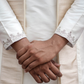 Close-up of hands held together wearing a beige traditional outfit with intricate patterns.