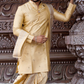 Man in a traditional cream-colored sherwani standing against an ornate architectural background