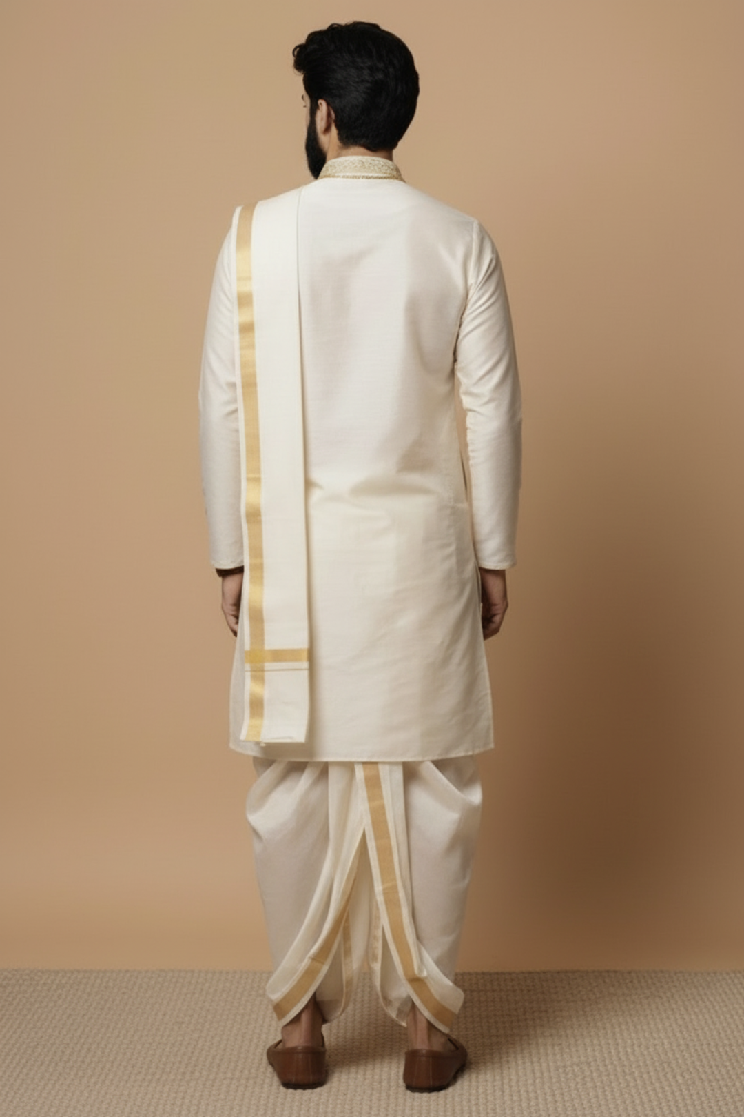 Man wearing a traditional cream-colored sherwani with gold accents against a beige background