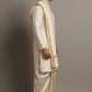 Man wearing a traditional cream-colored kurta with a matching dhoti against a plain background