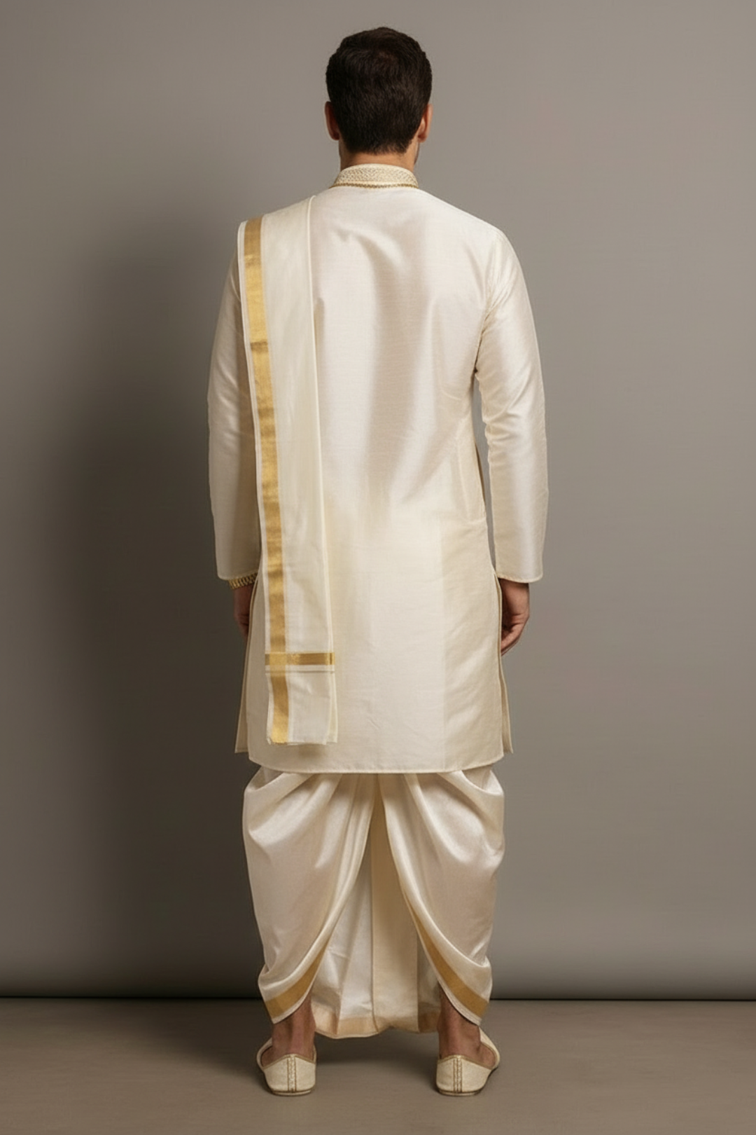Man wearing a traditional cream kurta with gold accents against a gray background