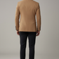 Man wearing a tan blazer and black pants on a gray background