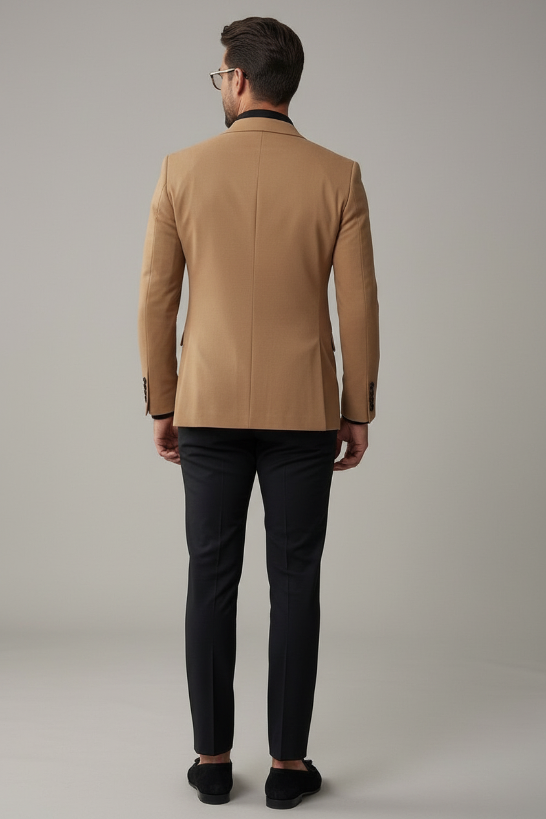 Man wearing a tan blazer and black pants on a gray background