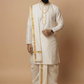 Man wearing a traditional white kurta with gold accents on a beige background