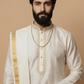 Man wearing a traditional white kurta with gold accents on a beige background