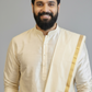 Man wearing a cream kurta with a beige shawl against a gray background