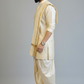 Man wearing a traditional cream kurta with a white dhoti on a gray background
