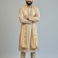 Man wearing a traditional beige kurta with a turban on a plain background