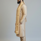 Man wearing a beige traditional outfit with a turban on a plain background
