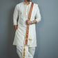 Man wearing a traditional white kurta with gold accents against a gray background