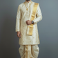 Man wearing a traditional cream kurta with gold accents against a gray background