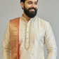 Man wearing a traditional cream kurta with a brown shawl on a gray background
