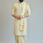 Man wearing a traditional cream kurta with gold accents on a plain background