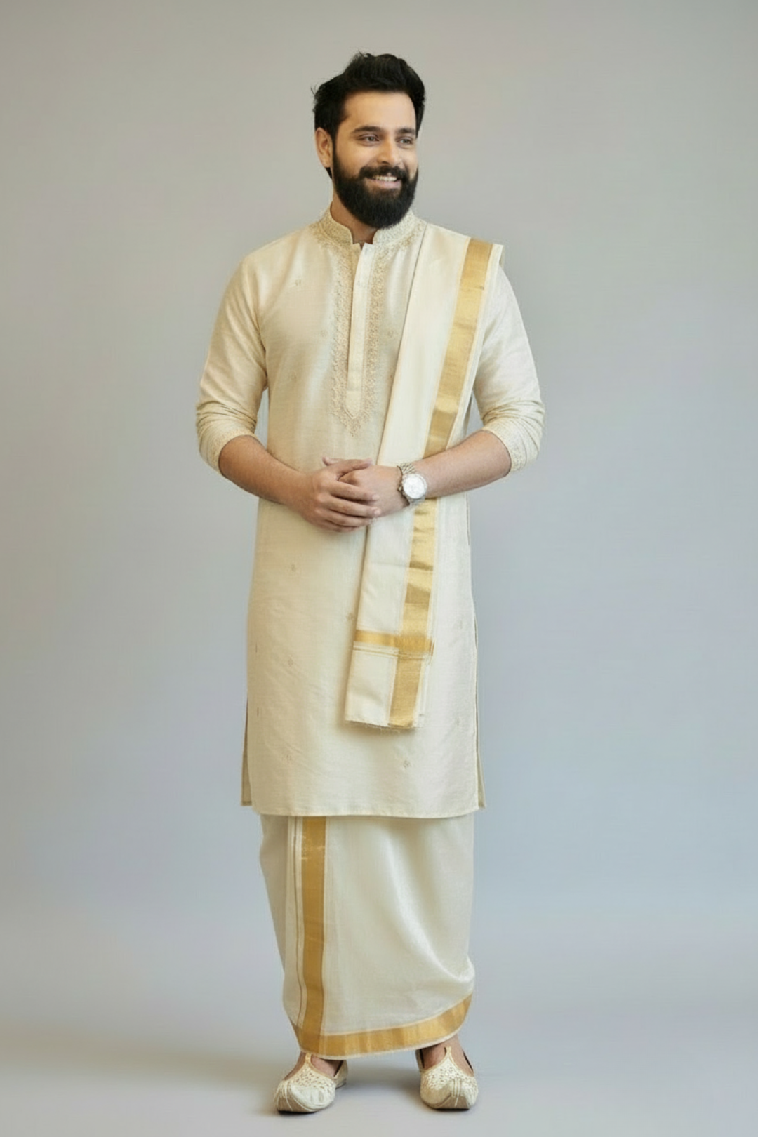 Man wearing a traditional cream kurta with gold accents on a plain background