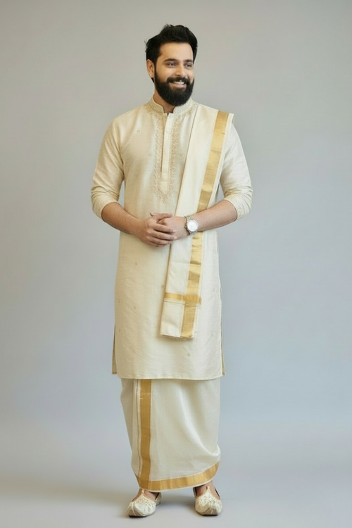 Man wearing a traditional cream kurta with gold accents on a plain background