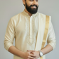 Man wearing a cream kurta with a gold border against a plain background