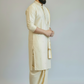 Man wearing a cream kurta with gold accents on a plain background