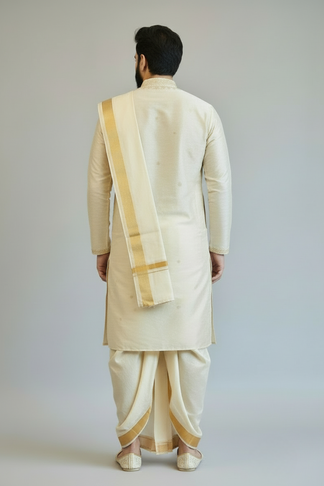 Man wearing a traditional cream-colored kurta with a white dhoti and gold border against a plain background