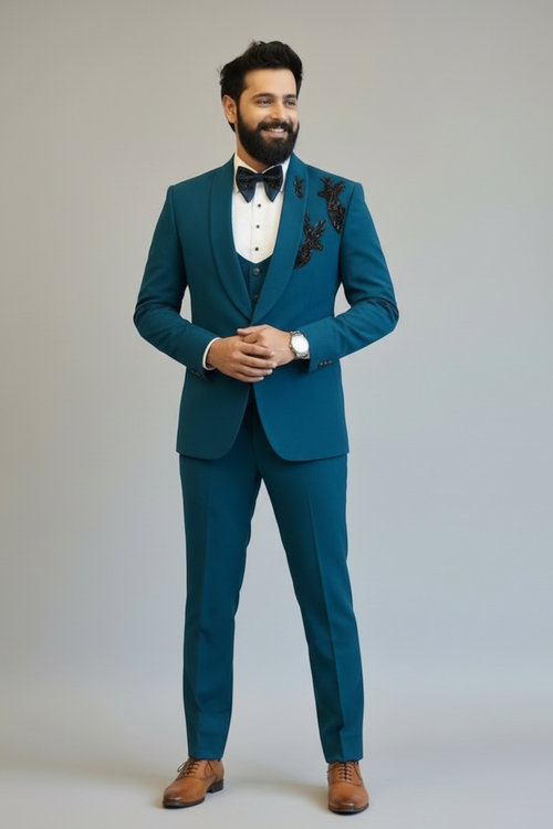 Man wearing a teal suit with a white shirt and brown shoes on a plain background