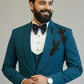 Man wearing a teal suit with black bow tie and floral embroidery on a gray background