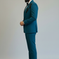 Man wearing a teal suit with brown shoes on a plain background