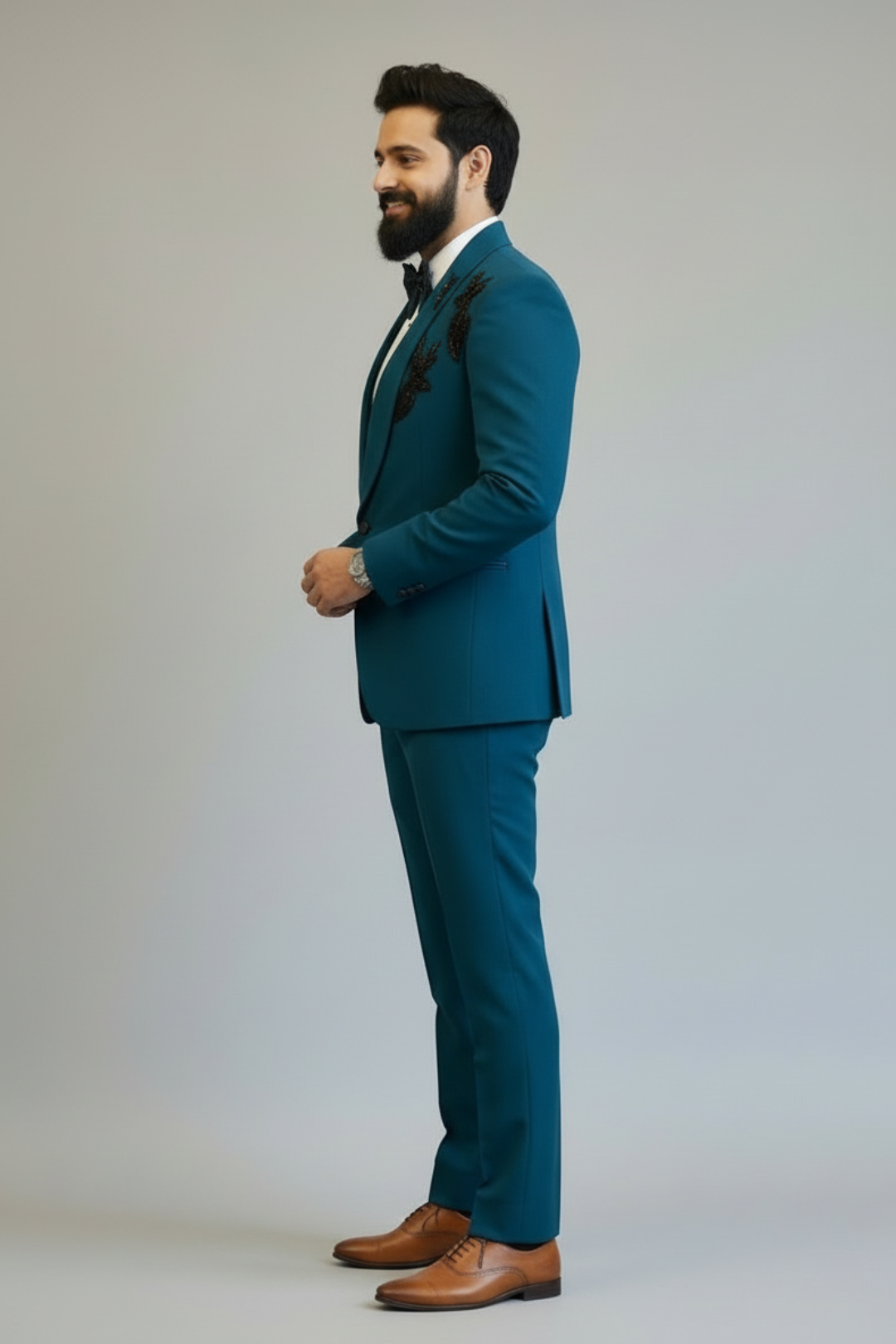 Man wearing a teal suit with brown shoes on a plain background