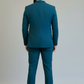 Man wearing a teal suit standing against a plain background
