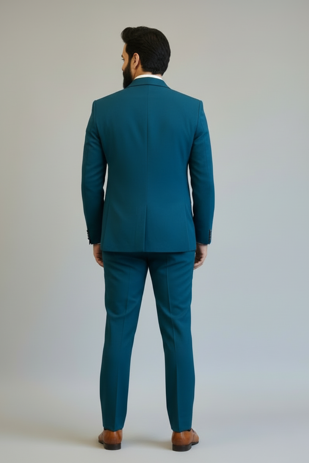 Man wearing a teal suit standing against a plain background