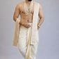 Man wearing a traditional white dhoti with gold accents on a gray background