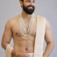 Man wearing a beige traditional outfit with gold jewelry on a gray background