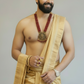 Man wearing a gold saree with jewelry on a plain background