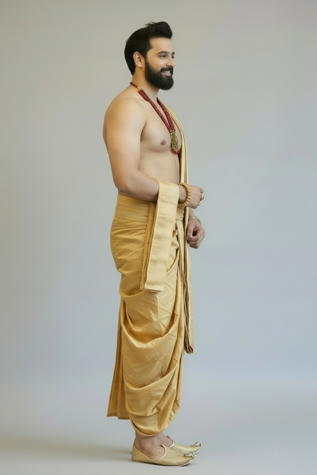 Man wearing a yellow dhoti against a plain background
