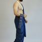 Man wearing a blue dhoti with a white cloth over his shoulder against a plain background
