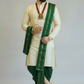 Man wearing a traditional outfit with a green and gold sash on a plain background