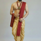 Man wearing a traditional gold dhoti with a red scarf on a plain background