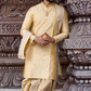 Man in a traditional yellow kurta standing in front of ornate stone architecture.
