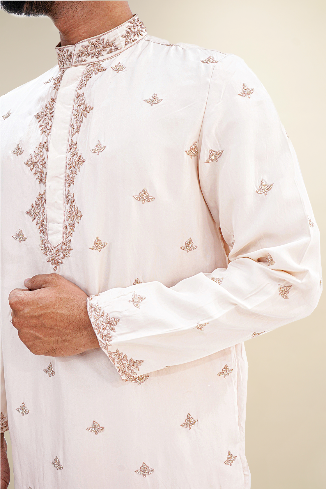 A man wearing a rose pink habutai kurta with zardozi butta work, standing with a smile.
