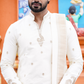 Man wearing a white embroidered kurta with a colorful background