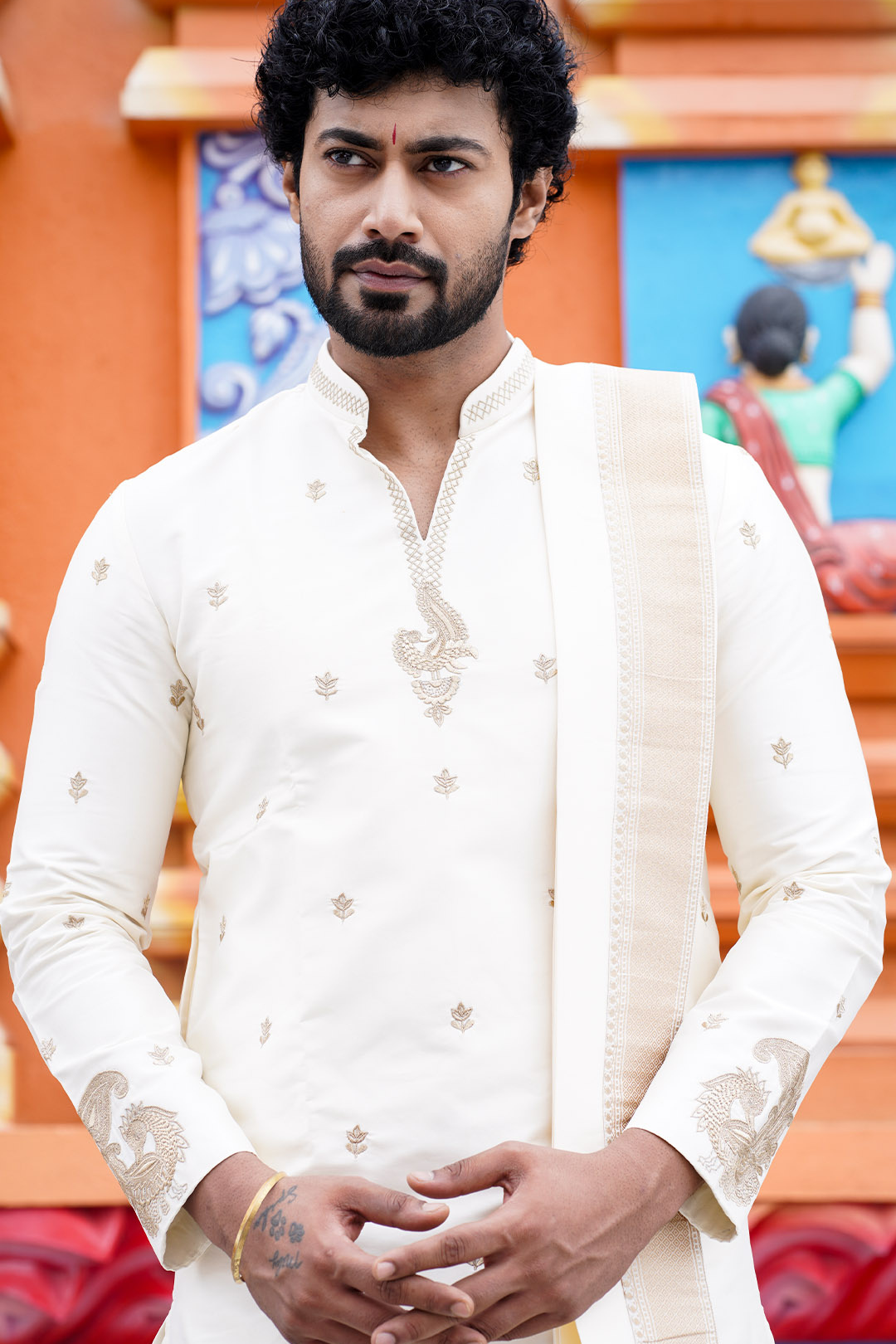 Man wearing a white embroidered kurta with a colorful background