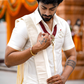 Man adjusting his necklace in a traditional setting