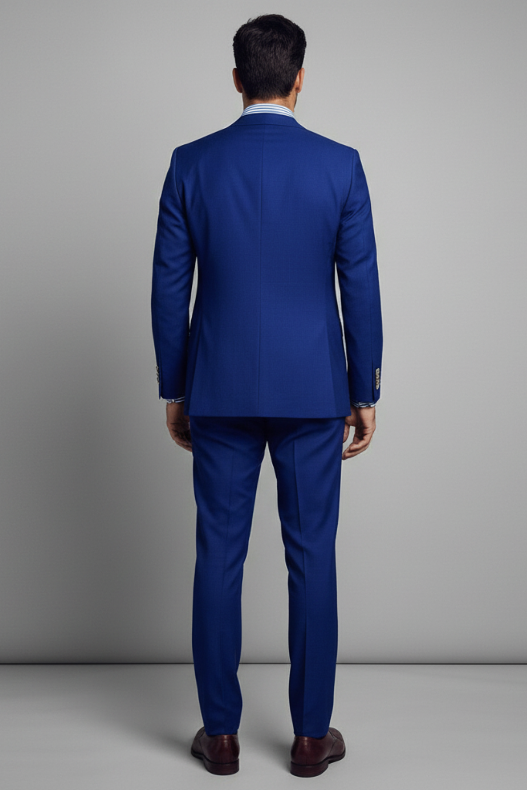Man wearing a blue suit standing against a gray background