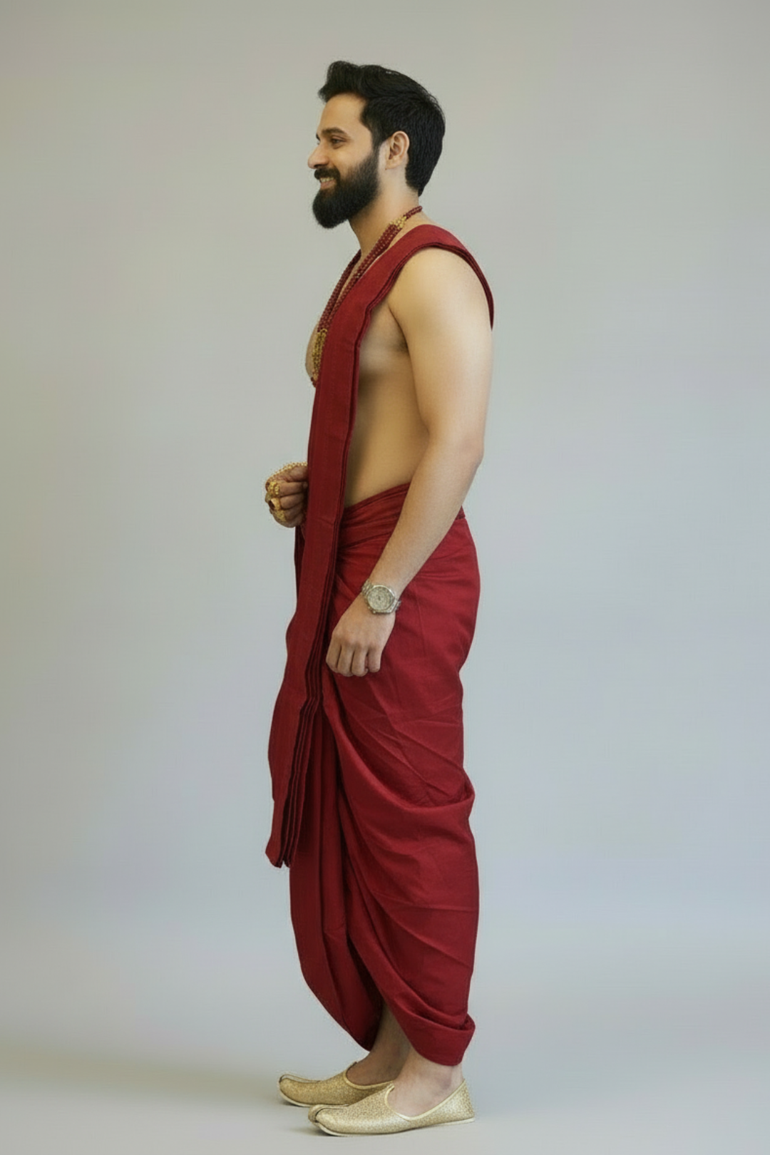Man wearing a red dhoti against a plain background